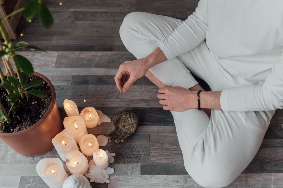 Person meditating indoors with candles and incense. A calm and peaceful setting for relaxation.